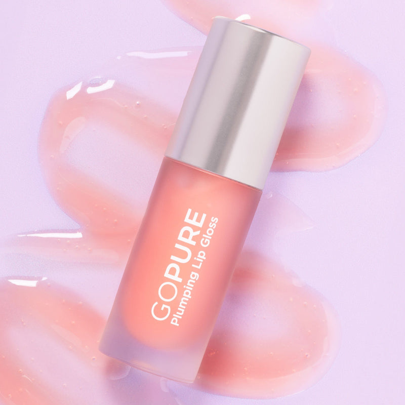 A GoPure Plumping Lip Gloss bottle on a lavender background, surrounded by glossy, peach-toned lip gloss smears. The product is labeled “GOPURE Plumping Lip Gloss.”